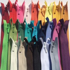 May include: Assortment of 24 zipper closures in various colors, including green, blue, red, yellow, white, and black. The zippers are arranged in rows and are all the same size.