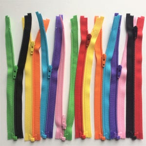Puede incluir: Surtido de 12 cierres de cremallera de colores. Las cremalleras est&aacute;n dispuestas en una fila y todas son del mismo tama&ntilde;o. Los colores son negro, amarillo, naranja, azul, morado, rosa, verde, rojo y azul claro.
