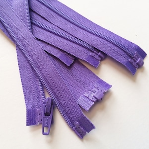 May include: A close-up of a bundle of purple zipper tape. The zippers are all closed and the slider is visible on one of the zippers.