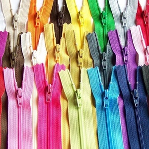 Puede incluir: Surtido de cintas de cremallera de colores en varios colores, incluyendo rojo, rosa, amarillo, azul, verde y morado. Las cremalleras están todas cerradas y tienen un deslizador de metal.