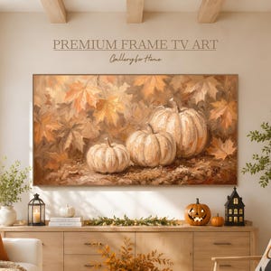 Può includere: Un'opera d'arte digitale rettangolare visualizzata su uno schermo televisivo che raffigura tre zucche bianche tra foglie autunnali cadute in tonalità arancione, oro e marrone, con il testo PREMIUM FRAME TV ART.