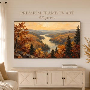 May include: A rectangular digital television display showing an oil painting of a landscape with a winding river, dense autumn forests in shades of orange, yellow, and brown, and distant mountains under a soft golden sky. The text reads PREMIUM FRAME TV ART.