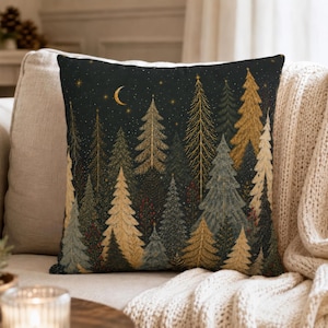 May include: A square throw pillow featuring a dark night sky background with a crescent moon and stars. The design displays a dense forest of evergreen trees in shades of gold, sage green, and muted blue, creating a layered, textured appearance.
