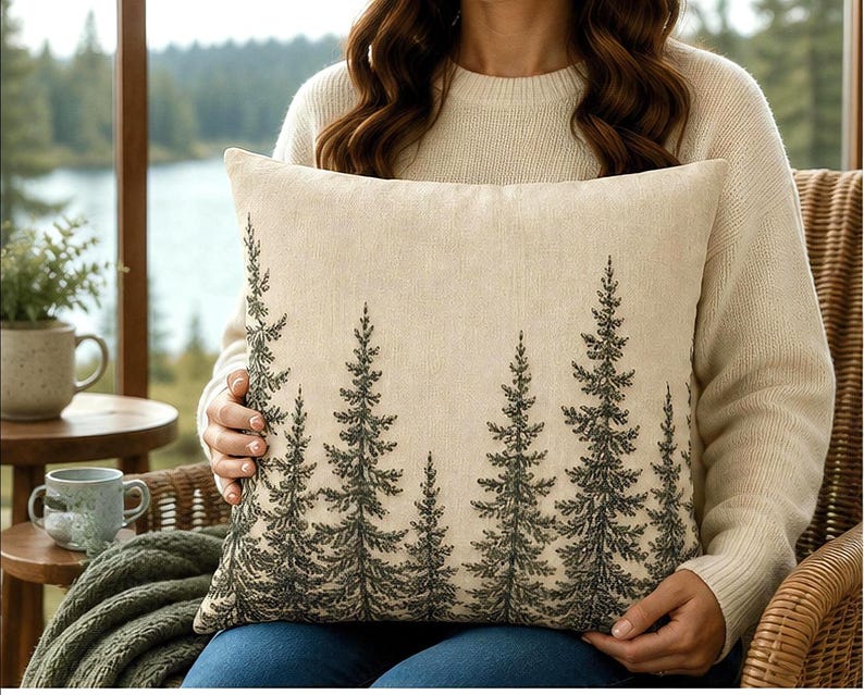 Rustic pine tree decorative pillow cover with woodland forest illustration on a neutral linen style background for cabin and lake house decor.