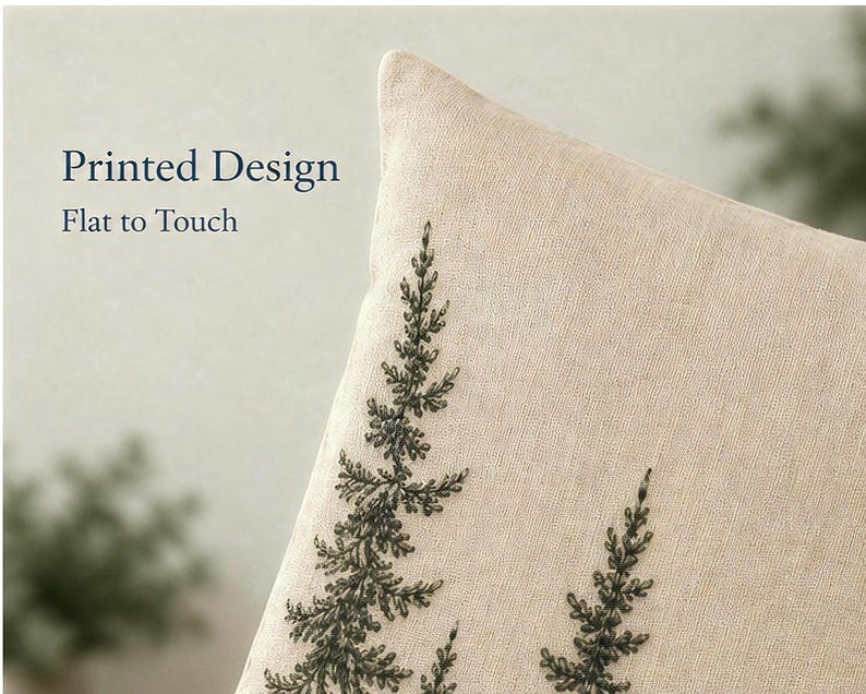 May include: A beige throw cushion cover featuring a dark green printed design of pine tree branches. The text Printed Design Flat to Touch is visible in the upper left corner. The fabric has a visible woven texture and a neutral light beige colour.