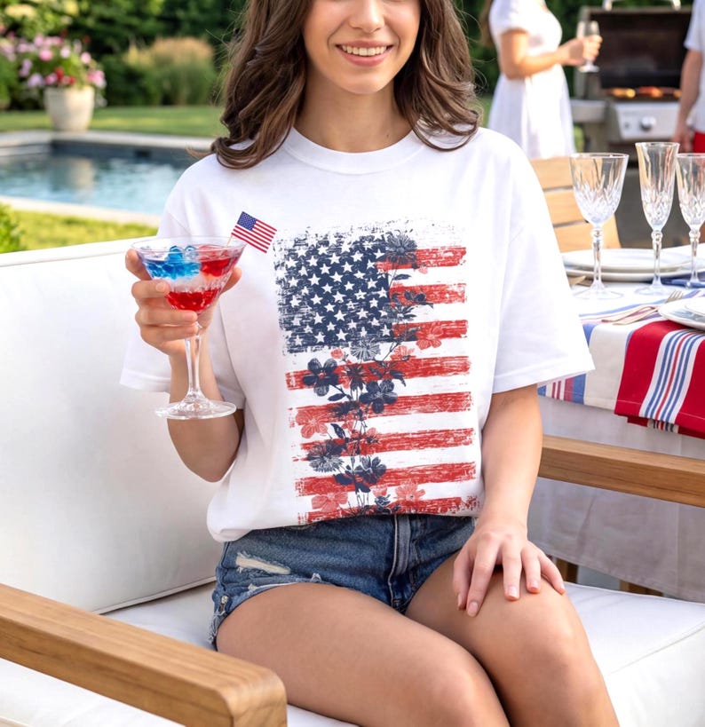 White comfort colors t-shirt with distressed american flag and subtle floral overlay, styled as patriotic summer graphic tee for women.