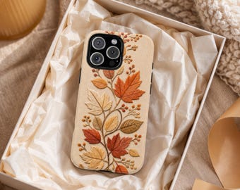 May include: A cream-colored phone case featuring an intricate embroidered design of autumn maple leaves and small berries in shades of orange, red, yellow, and brown, arranged in a climbing vine pattern across the back surface.
