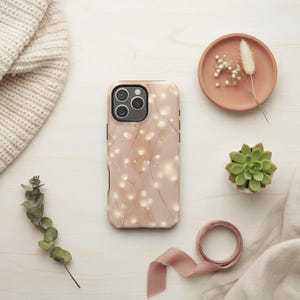 May include: A smartphone case featuring a soft beige background with a delicate pattern of thin, golden lines and small, glowing white circular lights, designed with a triple-lens camera cutout on the upper left corner.