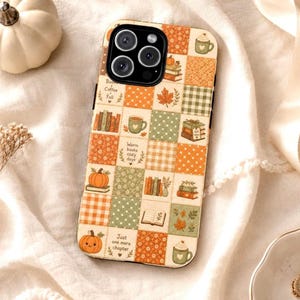 May include: A smartphone case featuring a patchwork design of autumn-themed squares in orange, cream, and sage green. The pattern includes illustrations of pumpkins, stacks of books, mugs of coffee, and leaves, with text reading Books Coffee Fall.