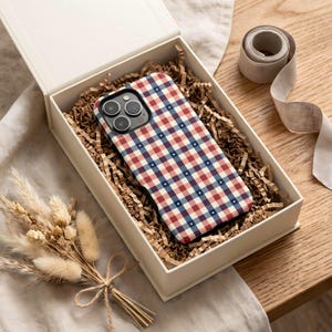 An iPhone case featuring a red white and blue plaid pattern with small star details in a classic Americana design. Ideal for a plaid patriotic iPhone case with preppy summer aesthetic.
