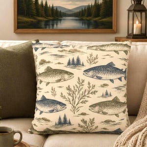 May include: A square throw pillow featuring a cream-colored fabric with a repeating pattern of various fish, pine trees, and aquatic plants in shades of blue, green, and brown. The design is printed across the front surface of the pillow.