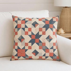 May include: Square throw pillow with a patchwork design in red, navy blue, and cream. The pillow features a star pattern made of various fabric squares and stripes. The pillow is on a white couch.