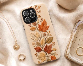 May include: A cream-colored smartphone case featuring a raised, textured design of autumn leaves and berries in shades of orange, brown, and gold. The case has a black camera cutout area and covers the back of the mobile device.