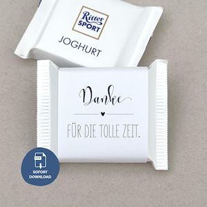 Könnte beinhalten: Zwei weiße Ritter Sport Schokoriegel. Auf einem Riegel steht das Wort "JOGHURT". Auf dem anderen Riegel stehen die Worte "Danke" und "FÜR DIE TOLLE ZEIT", mit einem kleinen Herzsymbol. Ein blauer Kreis mit den Worten "SOFORT DOWNLOAD" befindet sich in der Ecke.