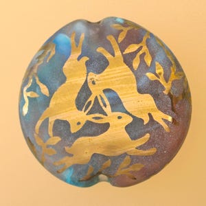 Handgemaakte glaskraal met drie hazen: folklore en raadsels