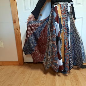 May include: A long, flowing skirt made from a variety of colorful fabrics. The skirt is a patchwork of different patterns and colors, including blue, red, yellow, and white. The skirt is gathered at the waist and falls to the ankles.