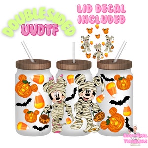 May include: Three white glass mason jar tumblers with wooden lids and straws. Each tumbler features a Halloween-themed design with Mickey and Minnie Mouse dressed as mummies, pumpkins, bats, and candy corn. The text "LID DECAL INCLUDED" is visible.