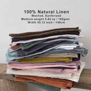 Puede incluir: Una pila de telas de lino de varios colores, incluyendo marrón, blanco, verde, gris, amarillo, rosa y naranja. La tela está etiquetada como 100% lino natural, lavada y sanforizada. El ancho es de 140 cm. El peso medio es de 165 g/m².