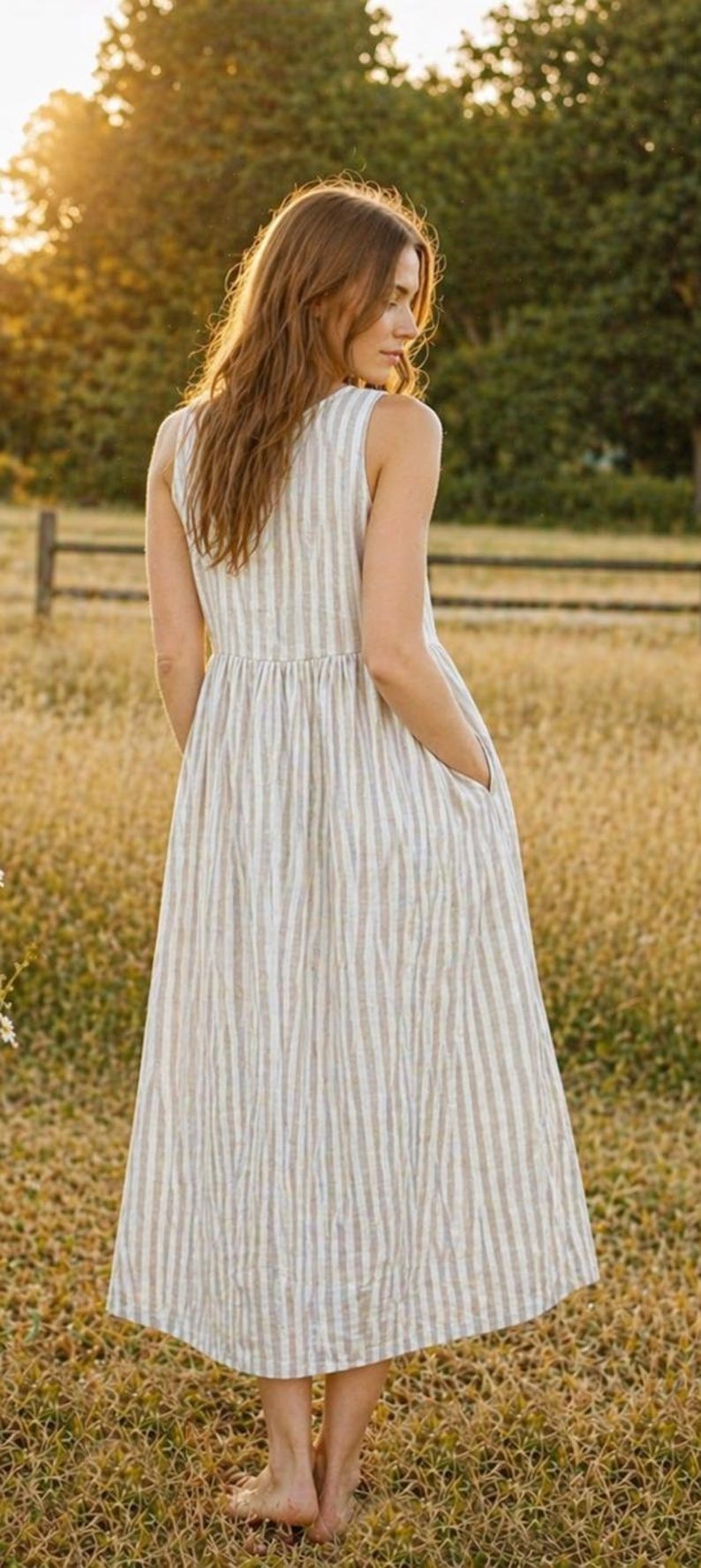 May include: A sleeveless midi dress featuring a vertical striped pattern in shades of beige and white. The garment has a fitted bodice, a gathered waistline, and a full, flowing skirt that includes side pockets, providing a simple and functional design.