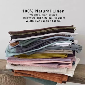 Puede incluir: Una pila de tela de lino natural en varios colores, incluyendo marrón, blanco, azul y amarillo. La tela está etiquetada como 100% lino natural, lavada y sanforizada. El ancho es de 140 cm (55,12 pulgadas).