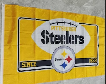 May include: A yellow flag with a white football design. The football has the words "Pittsburgh Steelers" and "Since 1933" on it. The Steelers logo is in the center of the football.