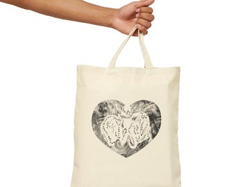 May include: A beige tote bag with a black and white heart design. The heart is made up of two anatomical hearts intertwined.