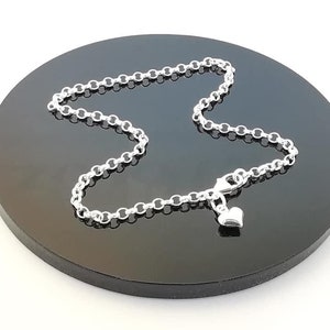 Peut inclure: Un collier en argent avec un petit pendentif en forme de cœur. La chaîne est de style câble délicat.