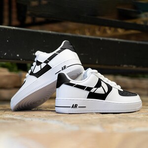 May include: A pair of white sneakers with black accents. The sneakers have a black swoosh design and the text "AIR" on the side.