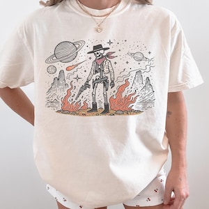 宇宙のカウボーイスケルトン、カウボーイエイリアンシャツ、ウエスタンUFO Tシャツ、ヴィンテージウエスタンTシャツ、カウボーイ宇宙Tシャツ、ヴィンテージレトログラフィックTシャツ