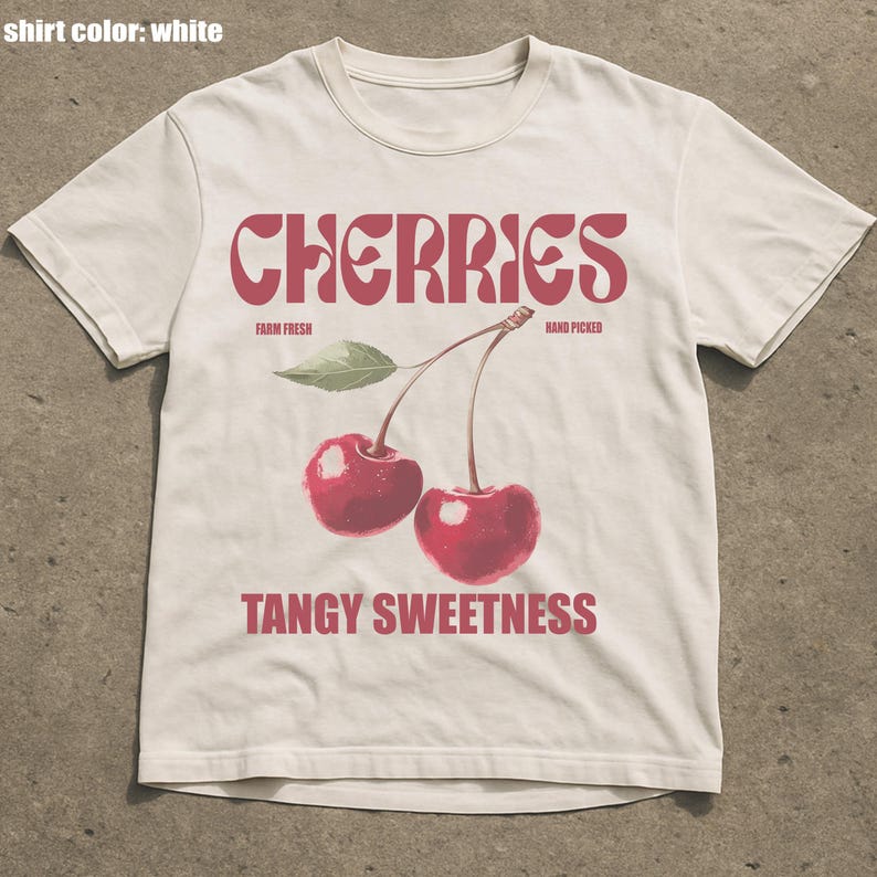 May include: White t-shirt with a red graphic of two cherries and the word "CHERRIES" in a stylized font. The text "FARM FRESH" and "HAND PICKED" are above the cherries, and "TANGY SWEETNESS" is below.