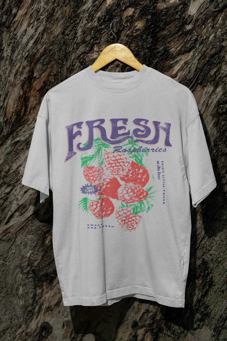 May include: A white t-shirt with a graphic print of raspberries and the text "FRESH Raspberries Enjoy Little Things While They Last Sweet Fresh And Fruity".