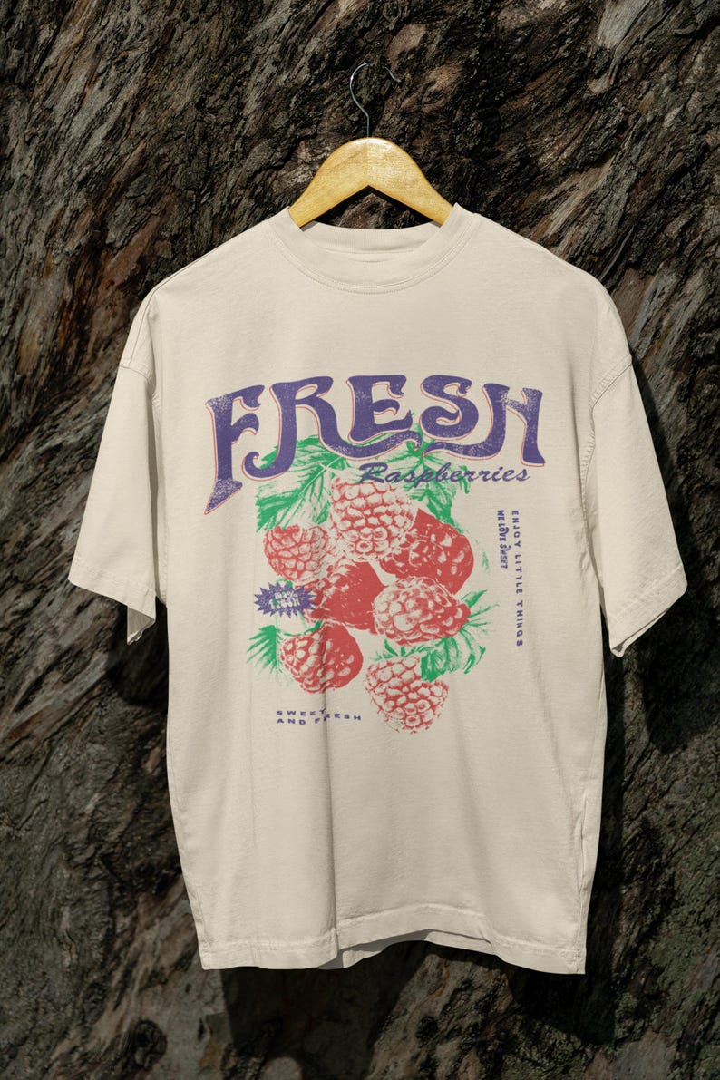 May include: A beige t-shirt with a graphic print of raspberries and the text "FRESH Raspberries Enjoy Little Things Sweet Fresh And Tart".