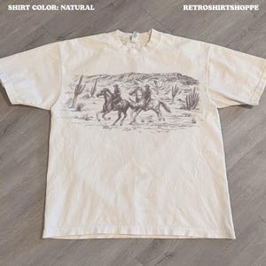 砂漠のカウボーイシャツ、ヴィンテージスタイルのウエスタンTシャツ、ウエスタングラフィックTシャツのオーバーサイズレディースシャツ、かわいいカウガールシャツ、レトロなワイルドウェストTシャツ