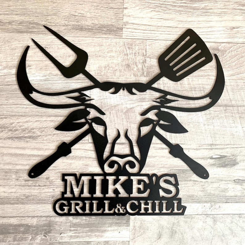 Black metal wall art featuring a bull's head with crossed grilling tools and the text "MIKE'S GRILL & CHILL".