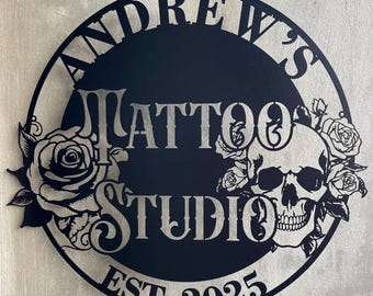 May include: Black metal sign with the text "Andrew's Tattoo Studio Est. 2025" in a circle with a skull and roses.