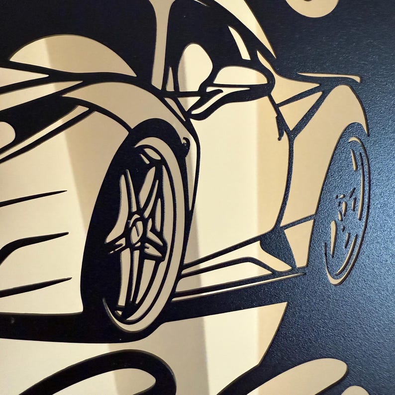 Op de afbeelding: Zwarte en gouden silhouet van een sportwagen met een gedetailleerd ontwerp van de wielen en de carrosserie. De auto is naar de rechterkant van de afbeelding gericht.