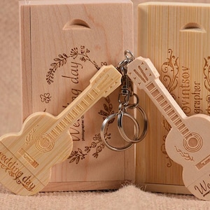 May include: Two wooden guitar-shaped USB drives with the text "Wedding day" engraved on them. The drives are in wooden boxes with engraved floral designs. One box has the text "Wedding day" engraved on it, and the other has the text "Photographer OwintSoy" engraved on it.