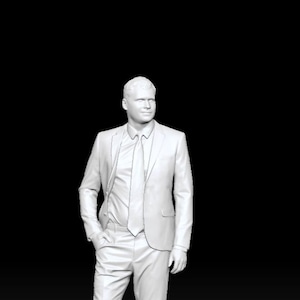 May include: A monochromatic white 3D figurine of a person standing in a formal suit, including a collared shirt, a necktie, a tailored blazer, and trousers. The figure is positioned in a standing pose with one hand in a pocket. Text reads IE_016.