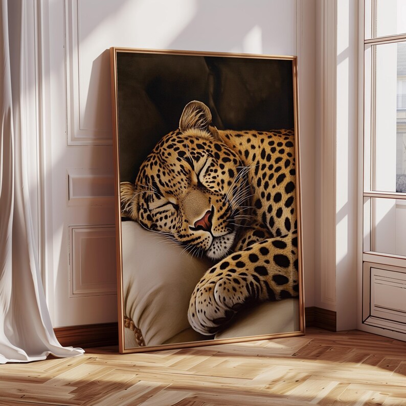 Pu&ograve; includere: Stampa artistica incorniciata raffigurante un leopardo addormentato. Il leopardo, con il suo manto maculato, riposa su un cuscino color crema. La cornice dorata contrasta con il muro bianco, creando un'atmosfera serena.