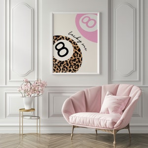 Puede incluir: Una impresi&oacute;n enmarcada en blanco con un dise&ntilde;o de bola 8 rosa y estampado de leopardo. El texto "lucky me" est&aacute; escrito en cursiva negra en la impresi&oacute;n.
