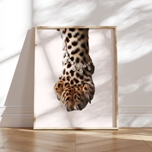 May include: A close-up of a leopard's paw with a diamond bracelet around the ankle. The paw is brown and black with sharp claws. The background is white.