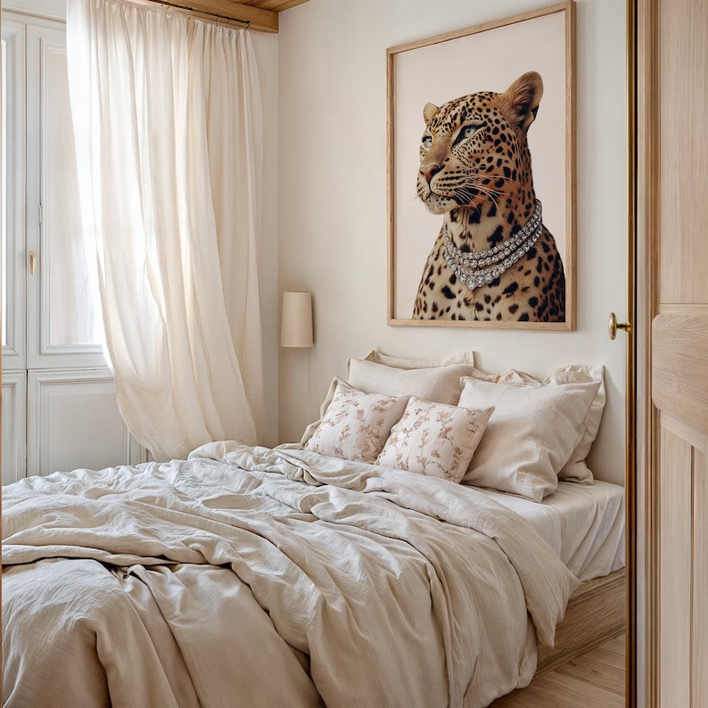 May include: A beige linen bed with a white and pink floral patterned pillow and a white pillow. A framed print of a leopard wearing a diamond necklace hangs on the wall above the bed.