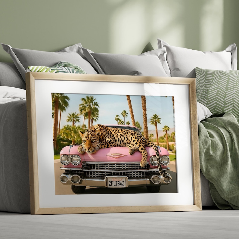Puede incluir: Una impresi&oacute;n enmarcada que presenta un coche rosa vintage con un leopardo descansando sobre el cap&oacute;. Las palmeras bordean el fondo bajo un cielo azul. La matr&iacute;cula del coche dice "2FLT842".