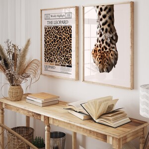 May include: Two framed prints with a leopard print theme. The print on the left features a close-up of a leopard print pattern with the text "The Leopard" and "Leopard" in a newspaper-style layout. The print on the right features a close-up of a leopard paw with a diamond bracelet around the ankle.