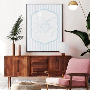 May include: A framed print featuring a light blue and white striped background with a light blue decorative border. Inside the border are two heart-shaped tags tied with ribbons. The tags have text on them.