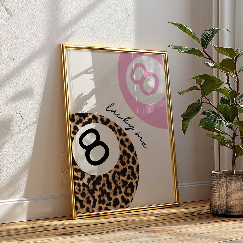 Puede incluir: Una impresi&oacute;n enmarcada con un dise&ntilde;o de bola 8 rosa y blanca y un dise&ntilde;o de bola 8 de estampado de leopardo. El texto "lucky me" est&aacute; escrito en cursiva en la impresi&oacute;n.