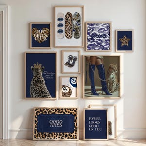 May include: A gallery wall of framed art prints with a fashion theme. Prints feature leopard print, lips, and text including "Hot Girls Club" and "Good Times". The colour scheme is navy blue, tan, and white.