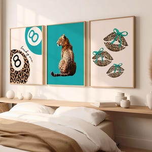 May include: Three framed art prints. The first features a leopard print eight ball with the text "lucky me". The second has a leopard sitting against a teal background. The third shows leopard print lips with teal bows.