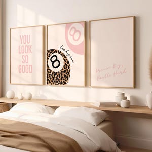 Könnte beinhalten: Drei gerahmte Kunstdrucke mit Zitaten. Der linke Druck zeigt den Text "YOU LOOK SO GOOD" in Rosa. Der mittlere Druck zeigt eine 8-Ball mit Leopardenmuster und dem Text "lucky me". Der rechte Druck sagt "Dream Big, Hustle Hard".