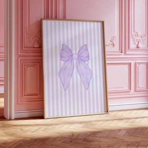 May include: A framed print with a purple watercolor bow on a white and purple striped background.